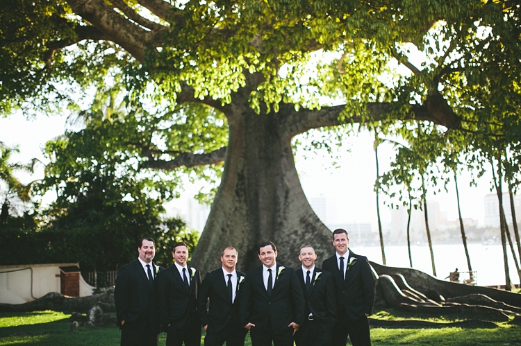 Groomsmen standing by giant tree at Royal Poinciana Chapel