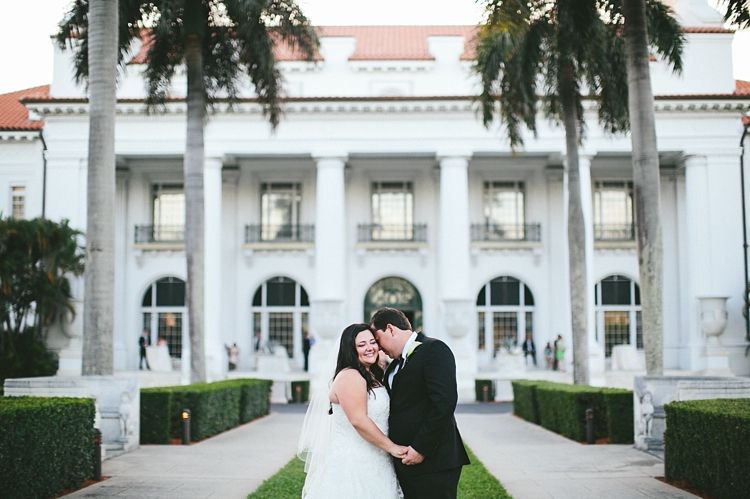 Bride and groom kiss in front of Flagler Museum 